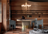 Curvo marble dining table beneath a chandelier in a wood panelled dining room