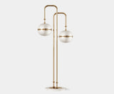Miles: Modern Floor Lamp in Gold-Plated Brass & Glass Globes. The Miles floor lamp by Mezzo Collection embodies modern grandeur. This striking piece features a flowing gold-plated brass frame cradling delicate glass globes, casting a warm and inviting glow in any modern living space. Inspired by the legendary Miles Davis, it creates a bold statement with its luxurious materials and captivating design.