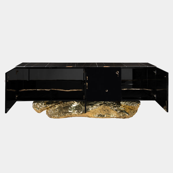 Modern black sideboard with a sculptural brass base and a sleek black marble top. The Angra Sideboard by Boca do Lobo offers ample storage and a touch of sophisticated style for your living room.