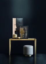 Duchessa channel quilted round pouf styled beneath a burnished brass console table