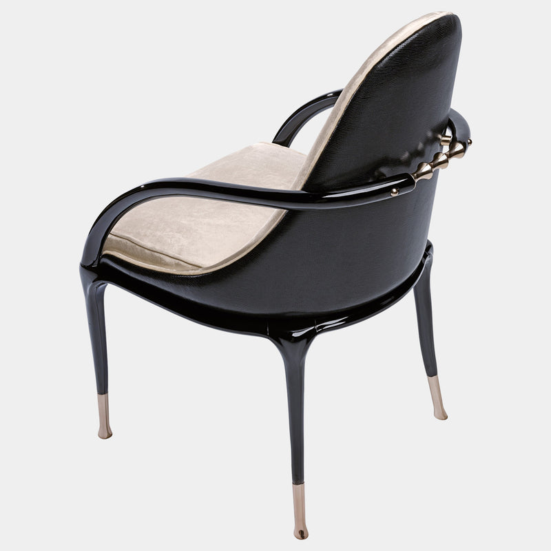 Unwind in Style: The Jera Padded Chair by Steve Leung. This modern seating option boasts a plush quilted velvet interior with a contrasting dark leather back, a sleek lacquered metal handle, and a variety of upholstery and metal finish options for a truly personalised look.
